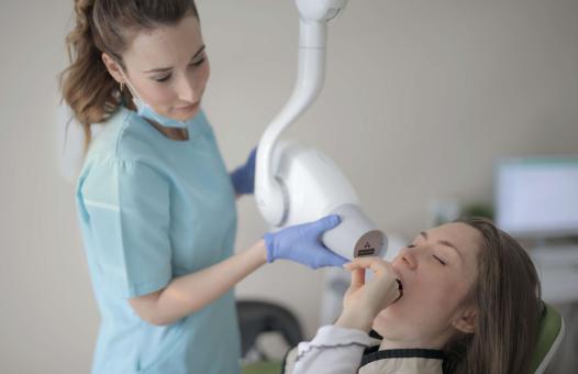 Pacjentka z bólem zęba na fotelu dentystycznym obok stojącej dentystki.
